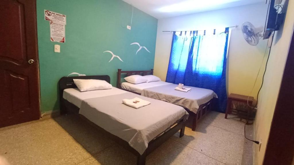 um quarto com duas camas e uma janela em Hotel Los Arcángeles em Cúcuta