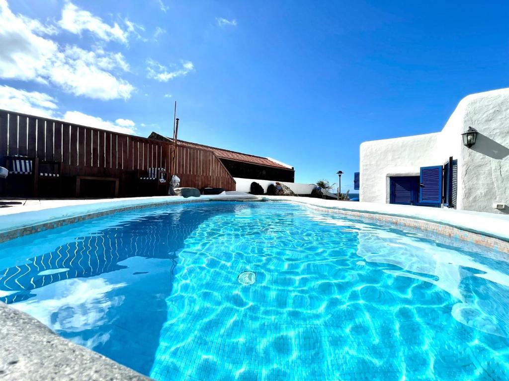 una piscina de agua azul frente a un edificio en Estupenda Villa con piscina privada, chimenea, frente al mar de Frontera, en La Frontera
