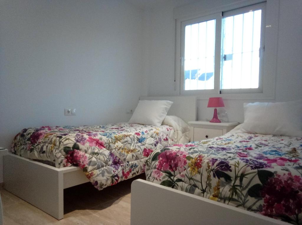 una camera con due letti e una finestra di Casa en Jerez con patio cerca de la playa y de la sierra a Jerez de la Frontera