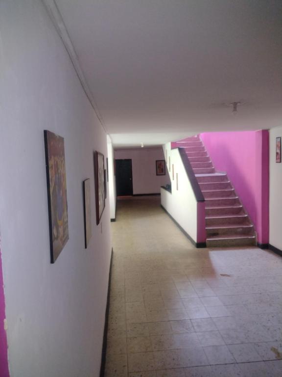 un pasillo con paredes rosas y escaleras en un edificio en Hotel el Manaa Santa Marta en Cúcuta