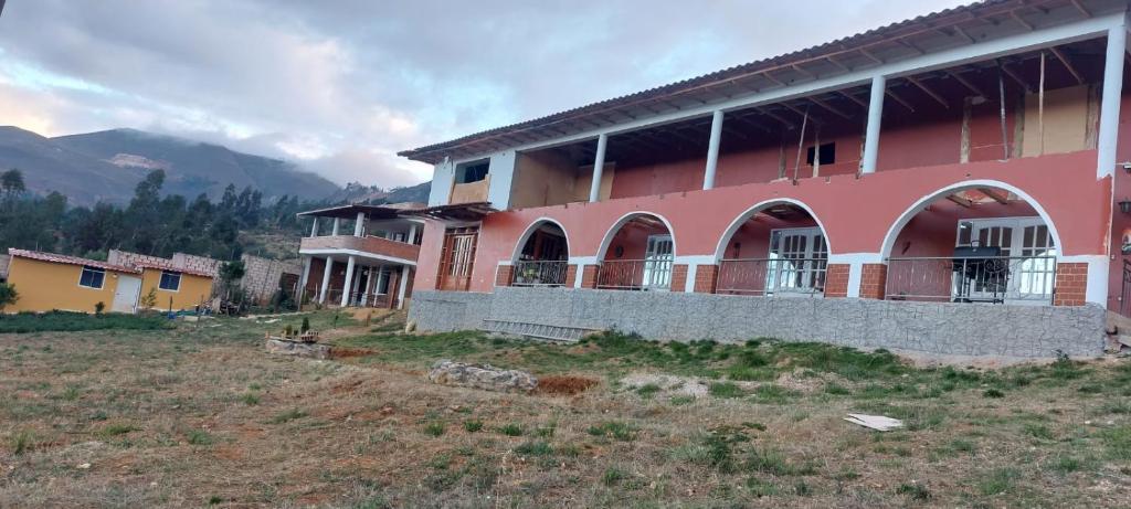 um edifício cor-de-rosa com janelas numa colina em Casa de campo completa a 20 minutos de Cajamarca Aire puro fogata y mas em Cajamarca