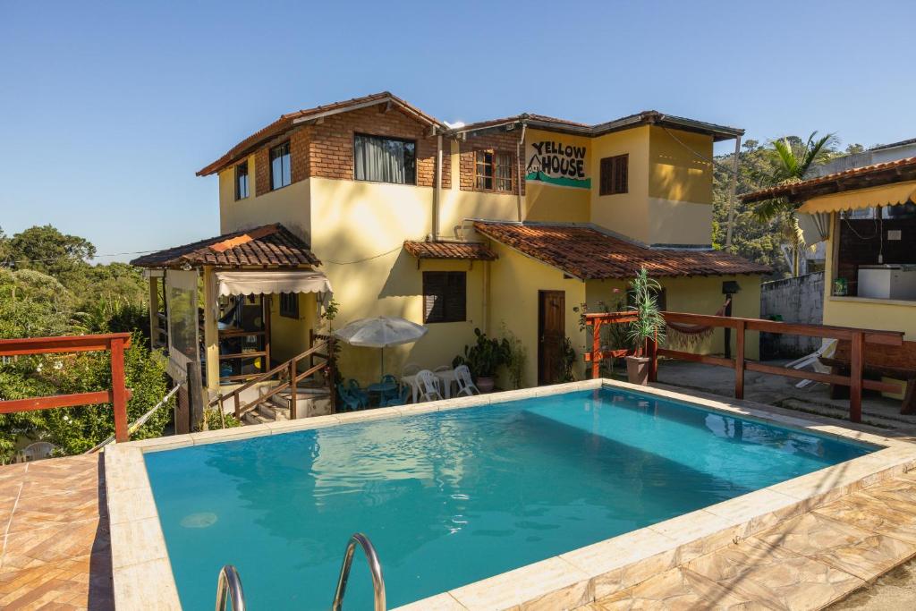 a villa with a swimming pool in front of a house at Hostel Yellow House MG in Itamonte