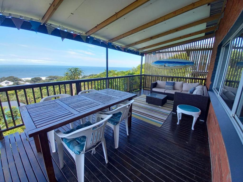 a deck with a table and chairs and a couch at Ocean rush Seagull in Zinkwazi Beach