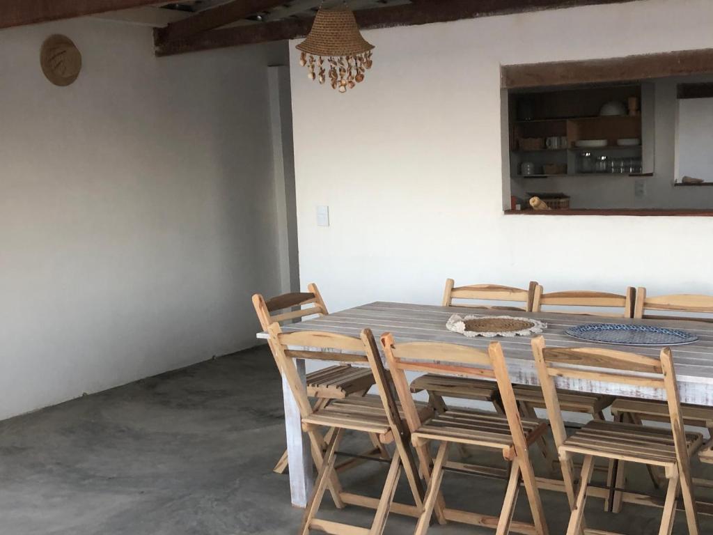 uma sala de jantar com uma mesa de madeira e cadeiras em CASA BRANCA NA PRAIA em Icapuí