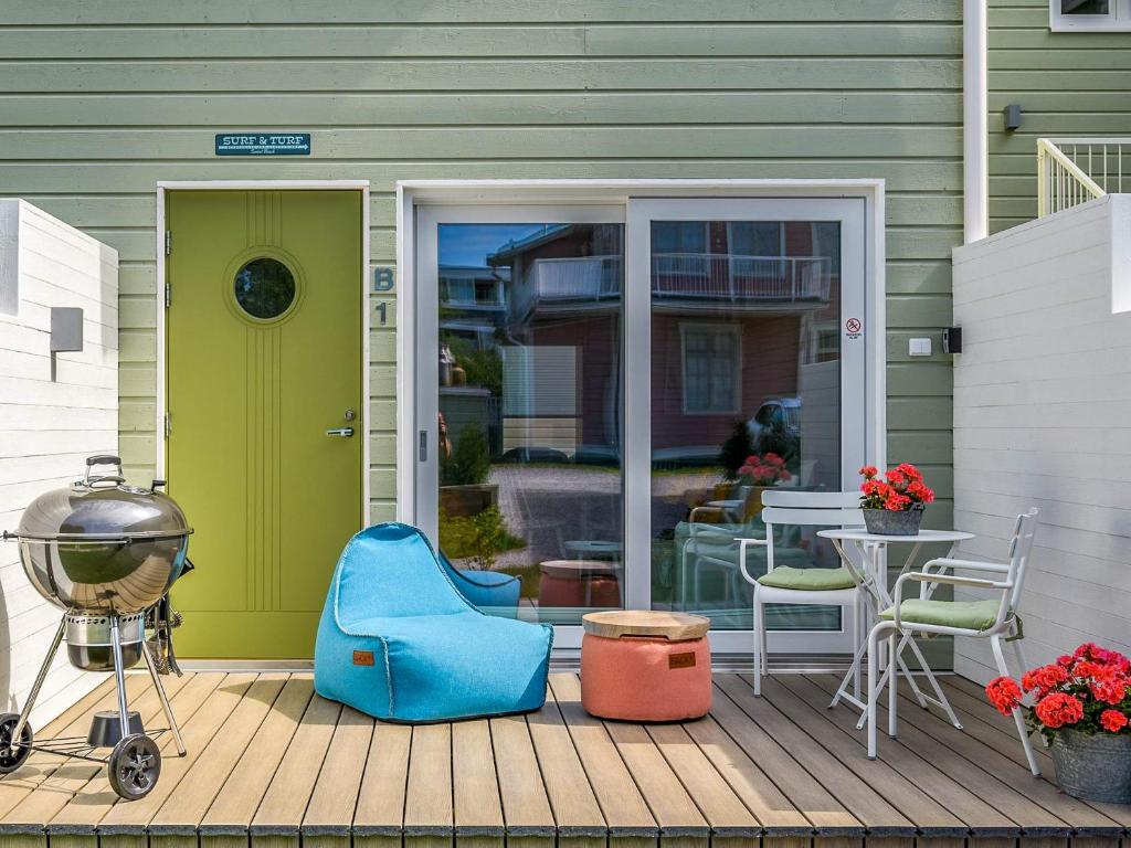 - une terrasse couverte à l'avant avec une porte verte, une table et des chaises dans l'établissement Surf and Turf Apartment in Hanko, à Hanko