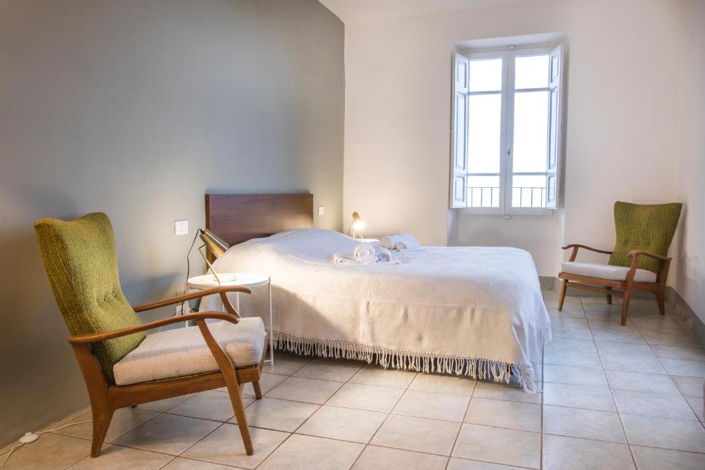 1 Schlafzimmer mit einem Bett, 2 Stühlen und einem Fenster in der Unterkunft Fontebella 46 in Assisi