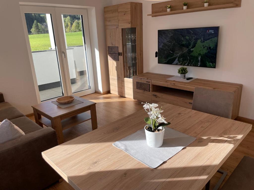 een woonkamer met een houten tafel en een televisie bij Mountain View Appartements mit Blick WEITBLICK in Innsbruck