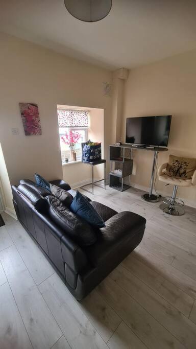 un sofá de cuero negro en una sala de estar con TV en Apartment 1, Regent Street en Bagenalstown