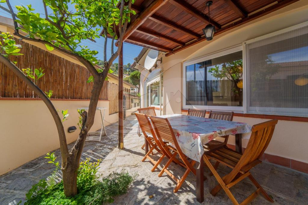 eine Terrasse mit einem Tisch, Stühlen und einem Baum in der Unterkunft Azzurro Mare a Seccheto - Goelba in Seccheto