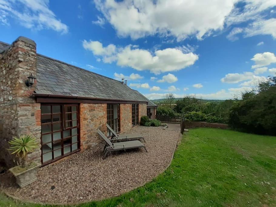 a stone house with a bench in the yard at Light & Airy Vaulted Barn Conversion with a View in Sampford Arundel