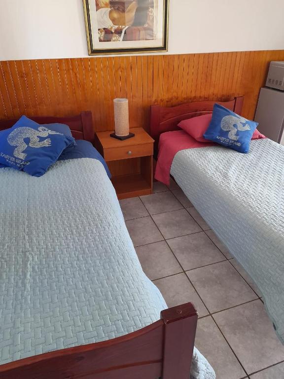 a room with two beds and a table with a lamp at Atavai Hotel Rapa Nui in Hanga Roa