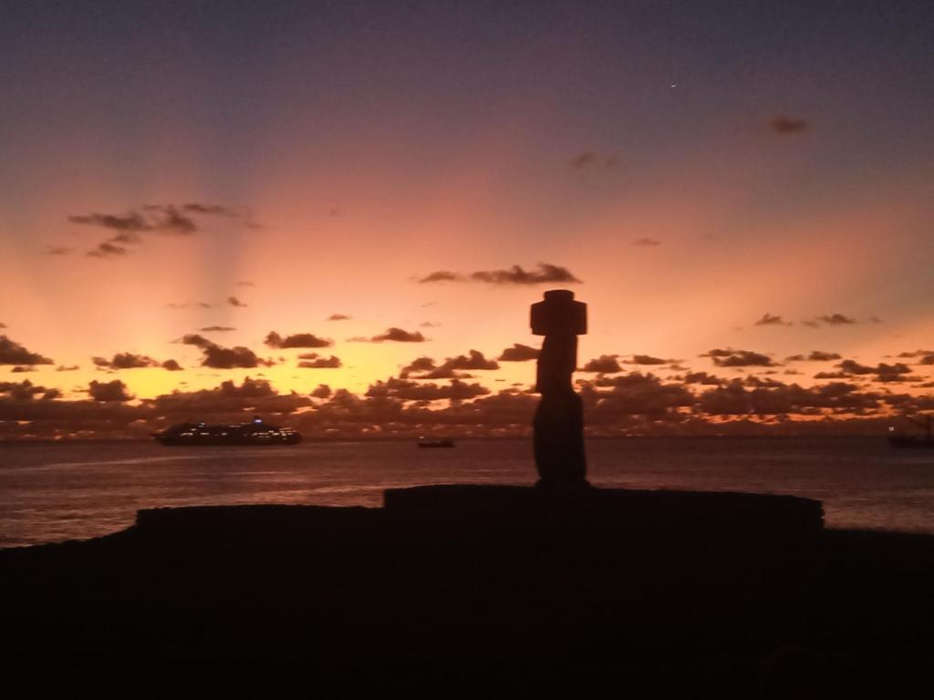 a silhouette of a statue in front of a sunset at Atavai Hotel Rapa Nui in Hanga Roa