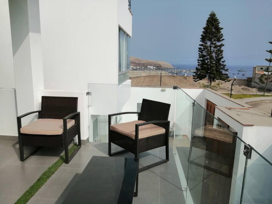 2 sedie sedute sul balcone di un edificio di Desestresate en la tranquilidad de la linda bahia a Pucusana