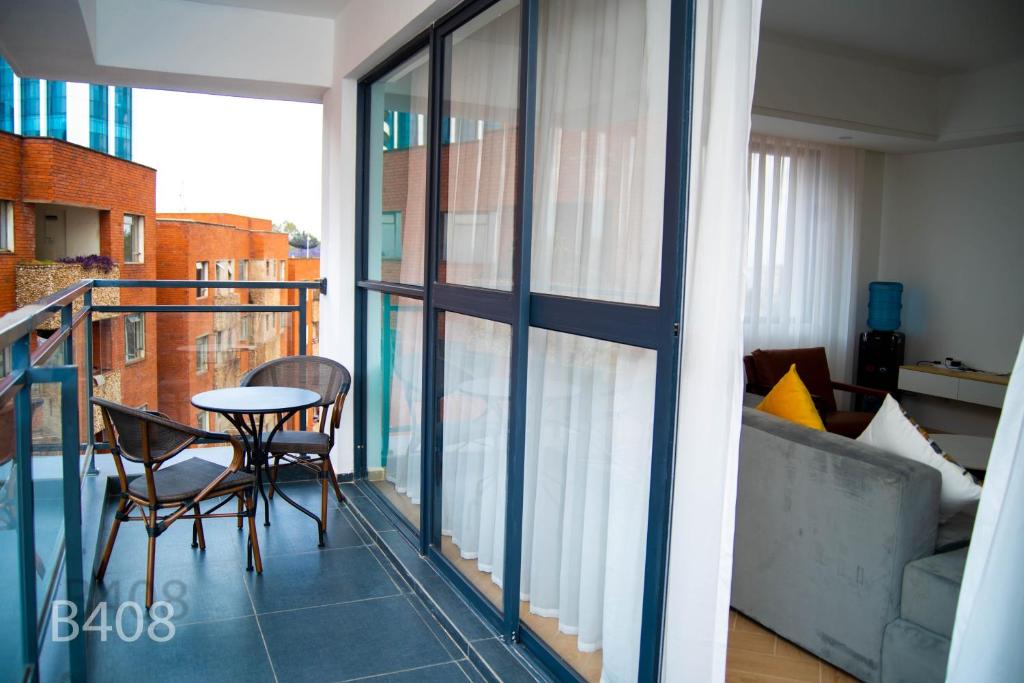 a balcony with a table and chairs and a couch at Laurel Living 2-Bedroom apartment in Nairobi