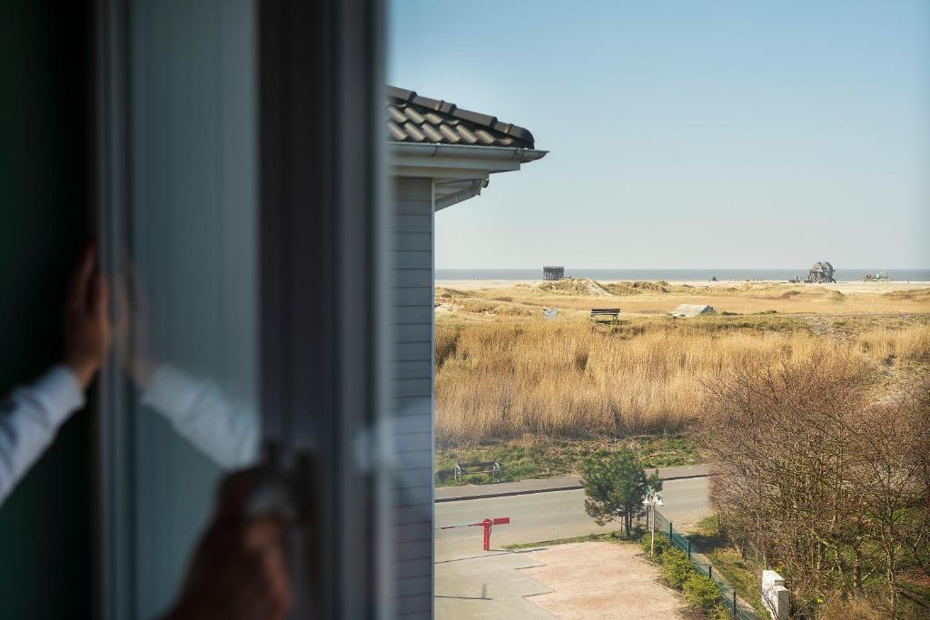 eine Person, die aus einem Fenster auf ein Feld blickt in der Unterkunft Beach Motel St. Peter-Ording in Sankt Peter-Ording