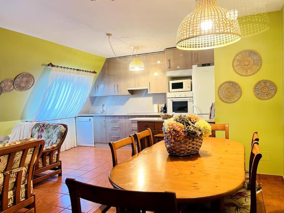 a kitchen with a wooden table with a vase of flowers on it at La Casa de Carmen in Malpica