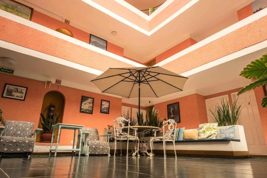 - un hall avec une table, des chaises et un parasol dans l'établissement HOTEL DEL VALLE INN IXMIQUILPAN, à Ixmiquilpan