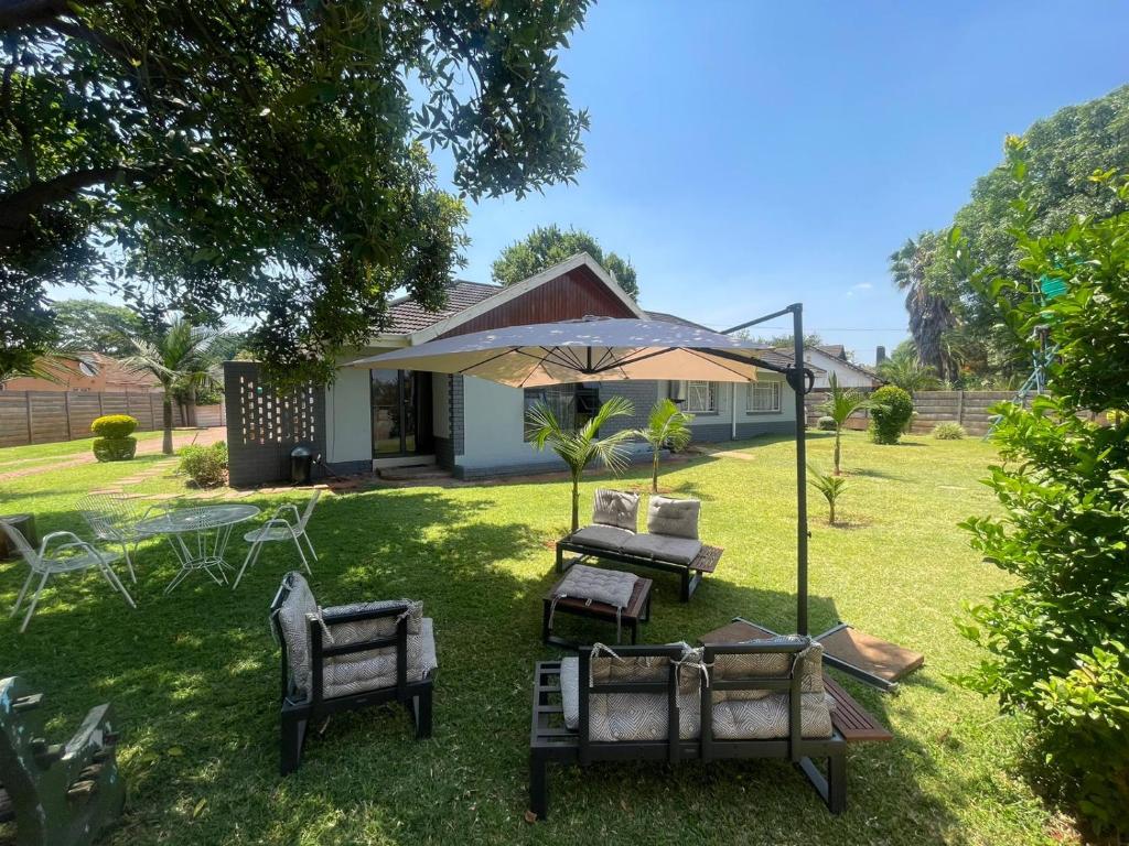 a group of chairs and an umbrella in a yard at The Hawks Bed and Breakfast in Harare