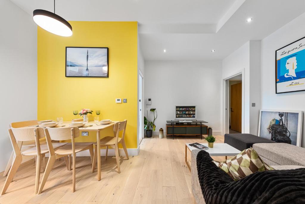 een woonkamer met een tafel en een gele muur bij Trendy 2 bed Flat in Greenwich with Car Parking in Londen