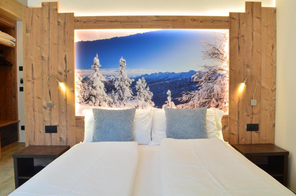a bedroom with a large white bed with a view at Aria Alpina Guest House Affittacamere in Predazzo