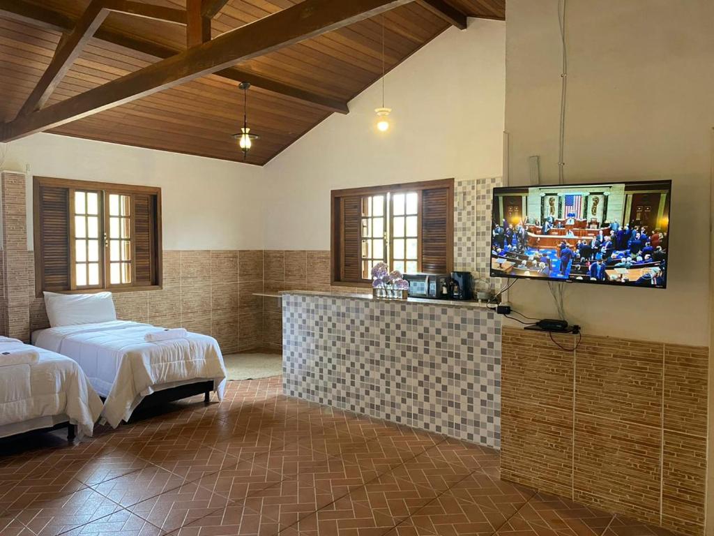 a bedroom with two beds and a flat screen tv at Chácara De Paula in Vassouras