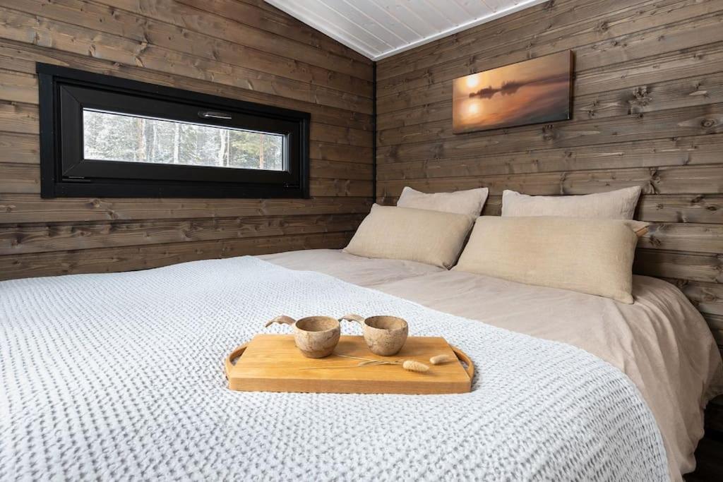 Una cama con una bandeja con dos tazas. en Tunnelmallinen ja ihana mökki, en Rovaniemi
