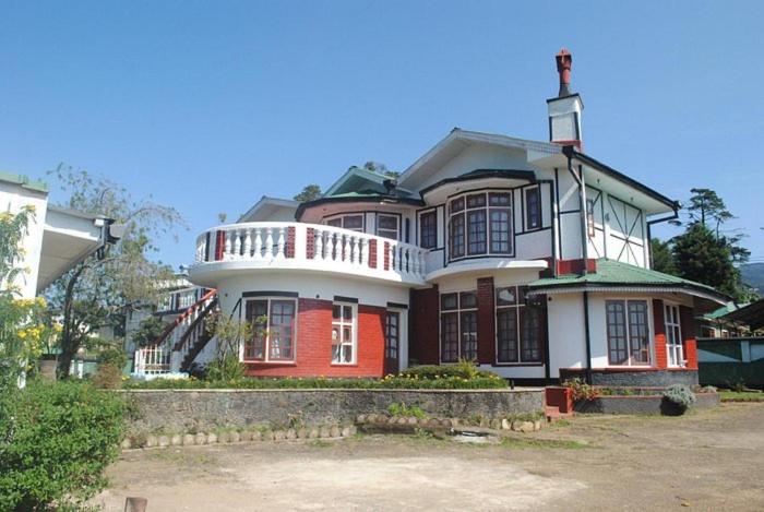 Casa grande de color rojo y blanco con porche en Heavenly Home Inn, en Nuwara Eliya