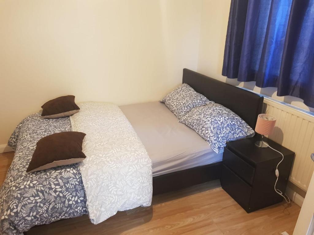 two beds in a small bedroom with blue curtains at A LOVELY STUDIO FLAT FEW MINTUES TO DAGENHAM EAST STATION in Dagenham