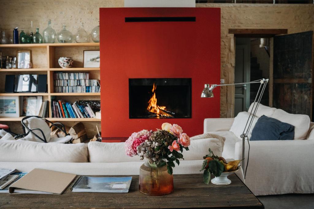 uma sala de estar com uma parede vermelha e uma lareira em Les Granges Pelloquin em Bernières-sur-Mer