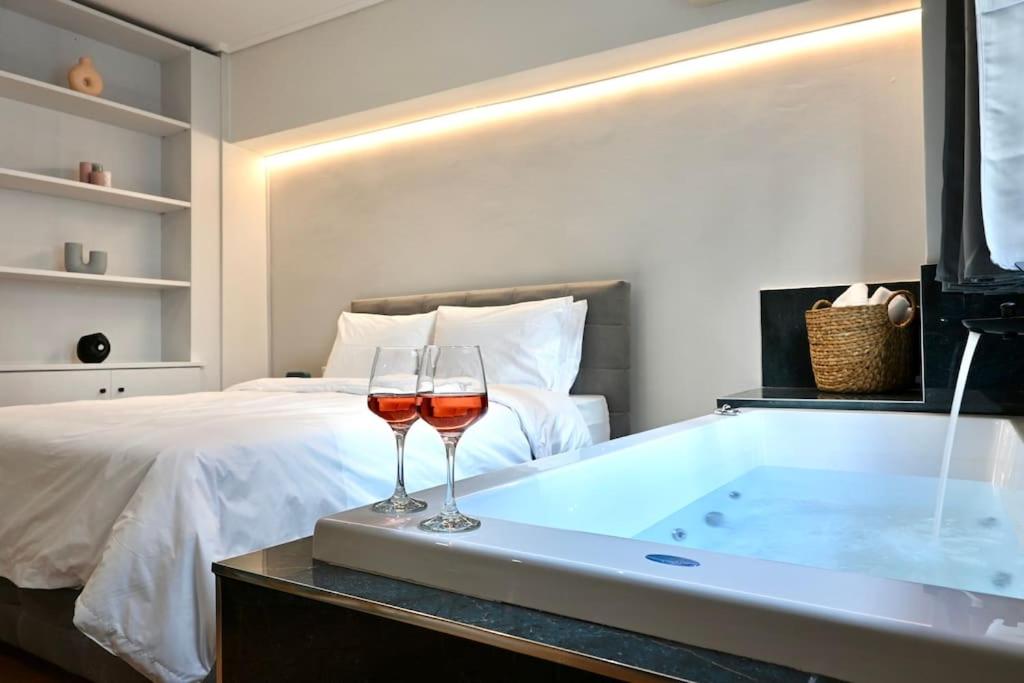 1 dormitorio con bañera y 2 copas de vino en Zoe's Suite Athen's Center, en Atenas