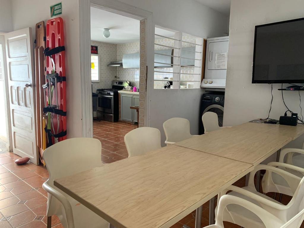 a dining room with a table and chairs and a kitchen at Hostel Mamy Dorme in Barranquilla