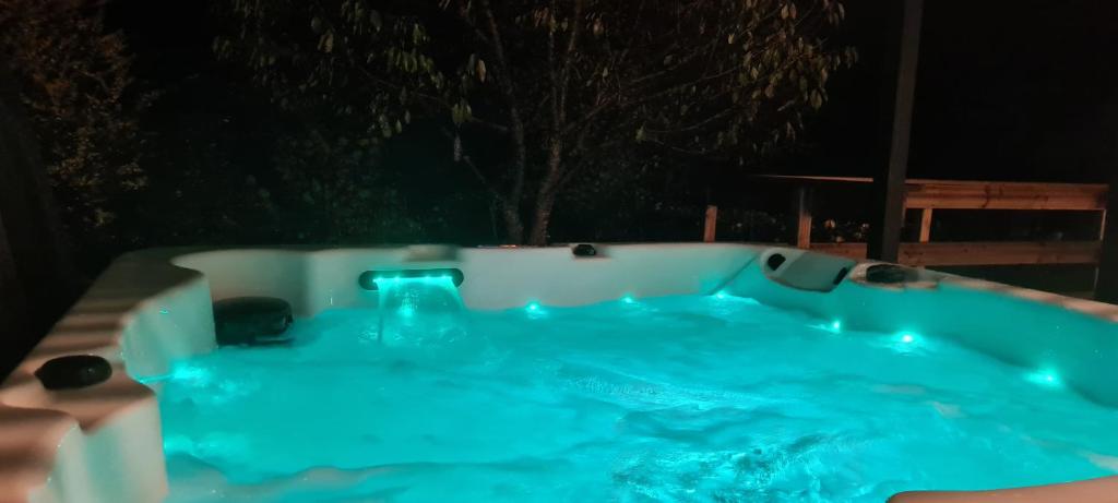 una bañera de hidromasaje con luces azules en un patio por la noche en Gîte 4 étoiles La Belle Eau Calme, en Futeau
