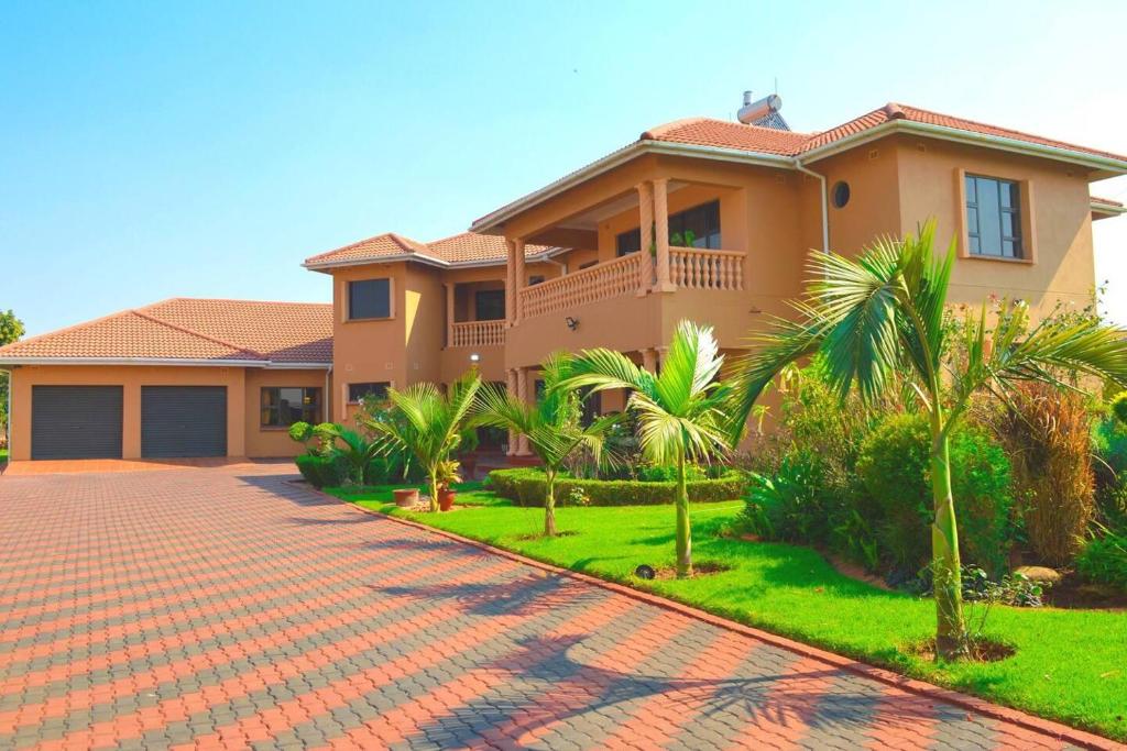 uma casa com palmeiras e uma entrada de tijolos em Mt Pleasant - 4-Bed Villa in Harare Solar Power em Kingsmead