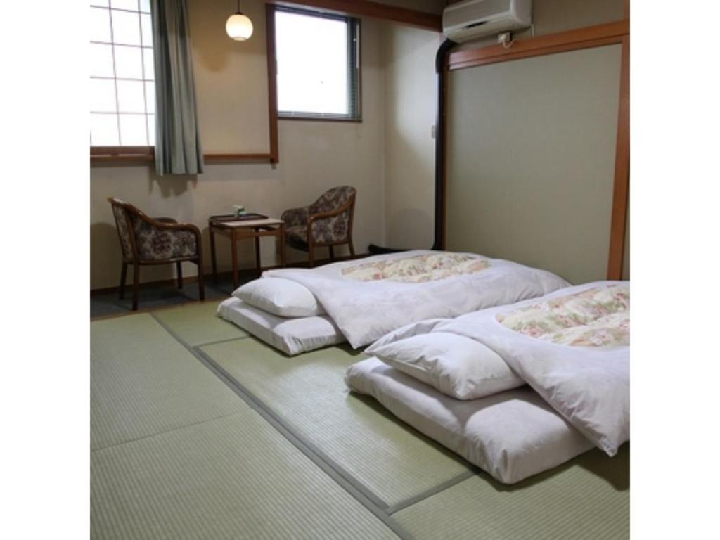 a room with two beds and a table and chairs at Tsukuba Town Hotel - Vacation STAY 65201v in Joso