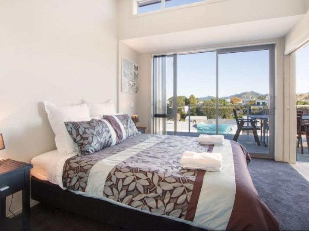 a bedroom with a bed with a view of a patio at Beach Pacific Apartments in Waihi Beach
