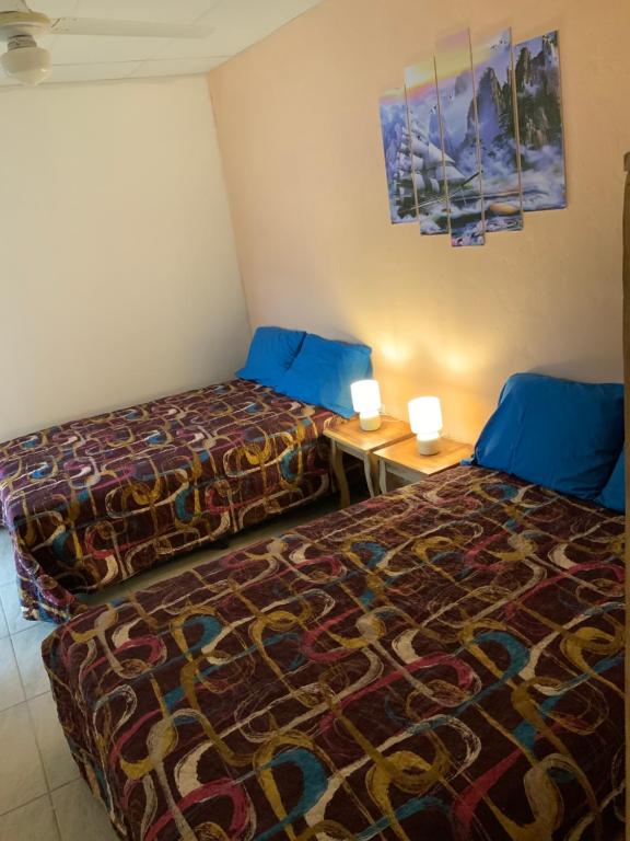 a room with two beds and a table with two lamps at HOTEL La DOLCE VITA FRANCOPHONE in Estelí
