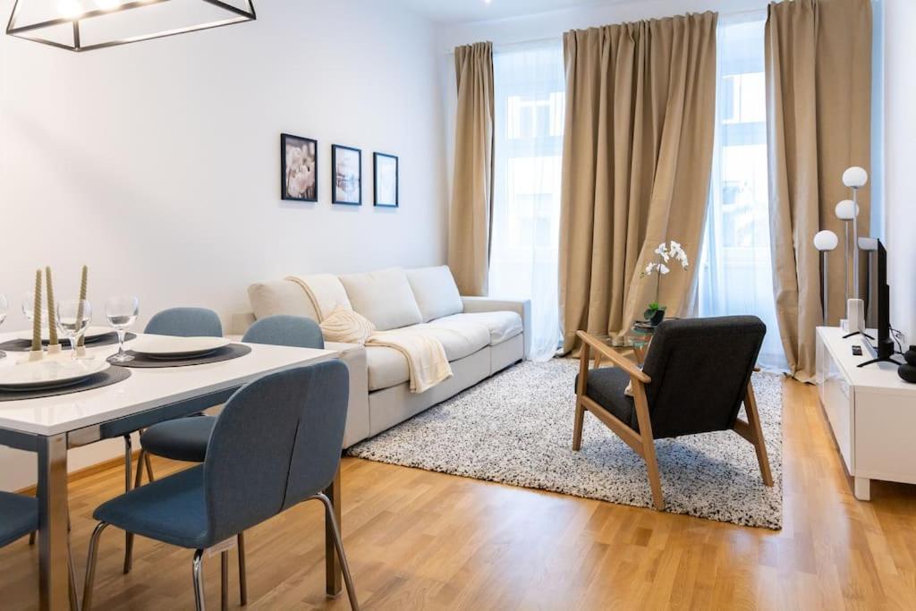 ein Wohnzimmer mit einem weißen Sofa, einem Tisch und Stühlen in der Unterkunft OrestaLiving - Danube Canal in Wien