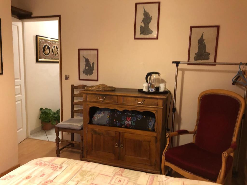 a room with a wooden cabinet and a chair at Chambre d’hôtes in Les Chapelles