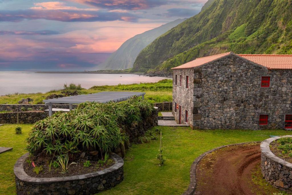 a stone building in front of a mountain at Kuanza Nature Experience, Fajã do Belo in Fajã da Caldeira de Santo Cristo