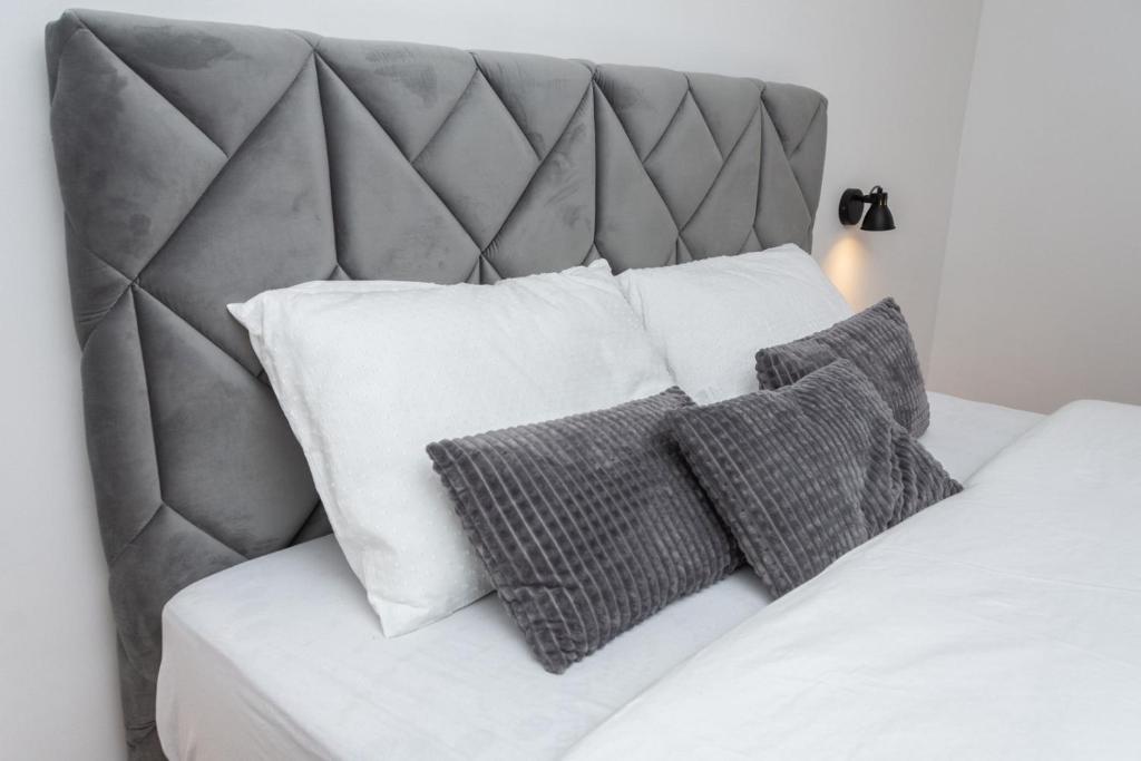 a bed with white pillows and a gray headboard at Apartment Marija in Pale