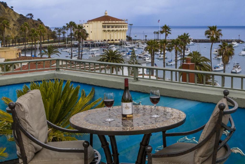 una mesa con 2 copas de vino en el balcón en The Avalon Hotel in Catalina Island, en Avalon