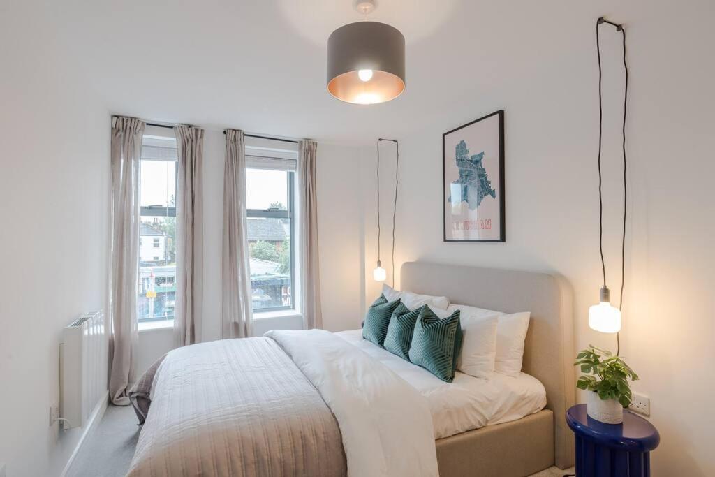 a white bedroom with a large bed with green pillows at The Ladywell in Lewisham in London