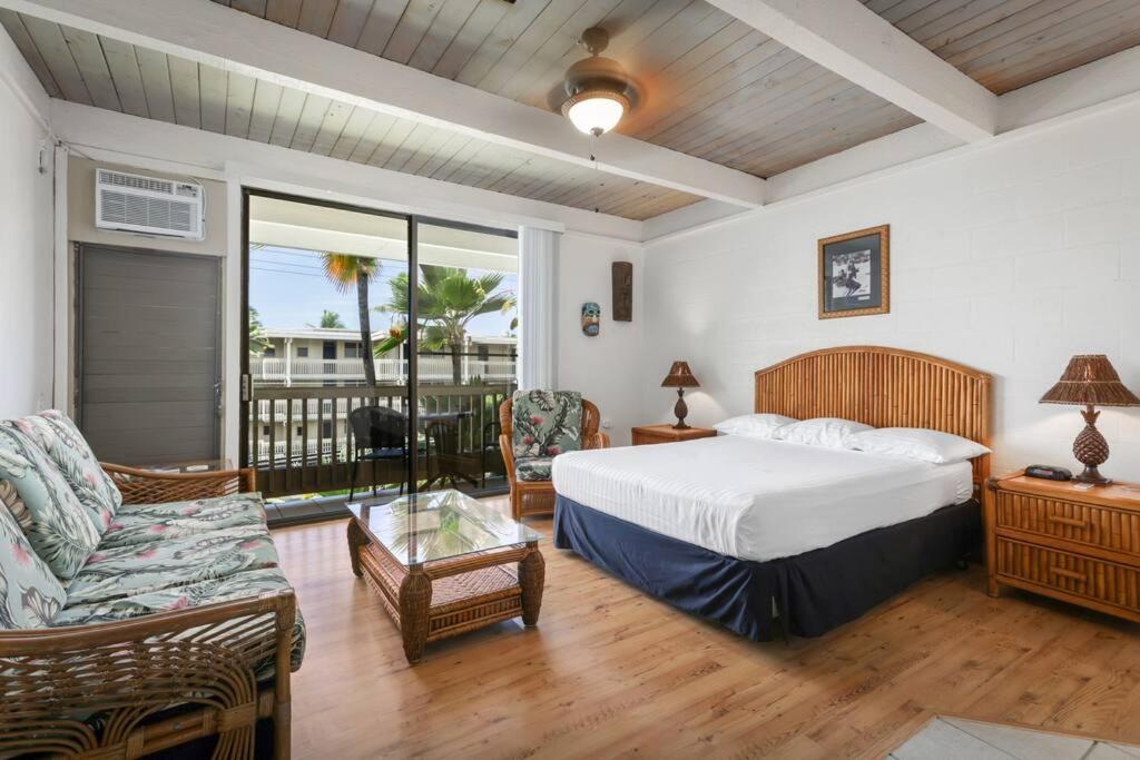 a bedroom with a bed and a couch and a window at Kona Bali Kai Unit 362 Partial Ocean View Studio in Kailua-Kona