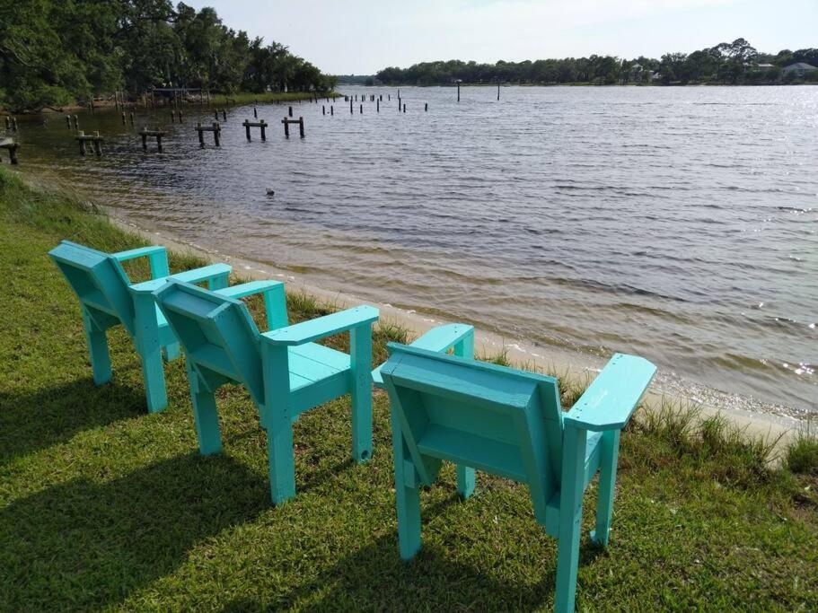 four blue chairs sitting on the shore of a body of water at Studio with Private Beach on Bayou Grande in Pensacola