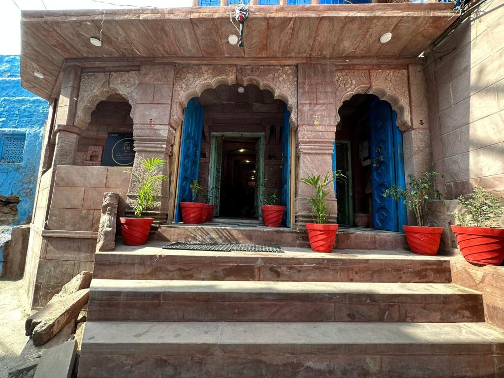 a building with blue doors and potted plants on the stairs at Geel Heritage - A Restored Haveli in Jodhpur