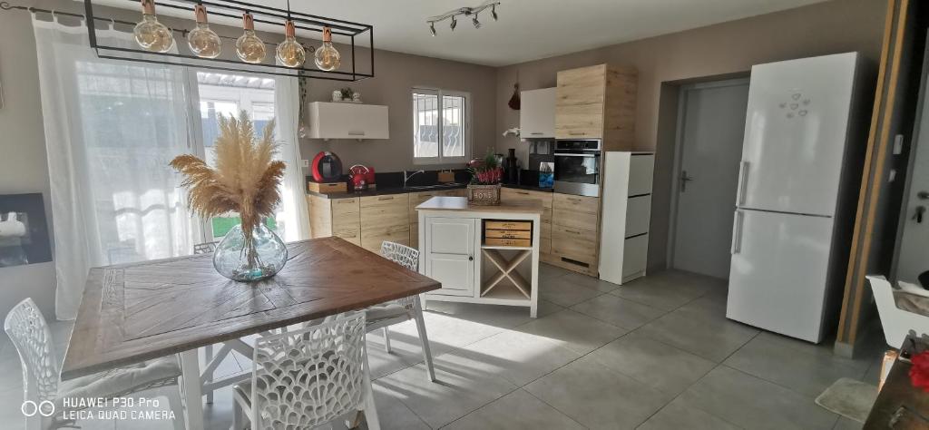 a kitchen with a table and a white refrigerator at Chambre Cosy non Fumeur in Châteaurenard