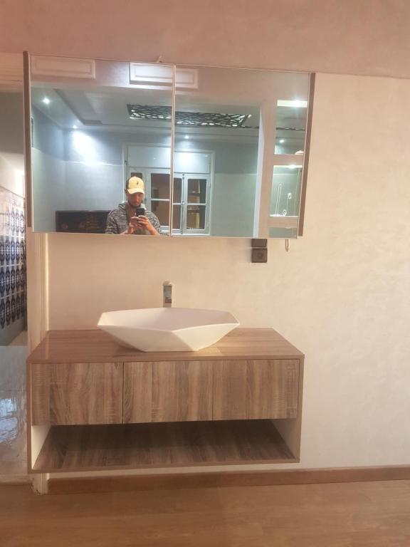 un hombre tomando una foto de un lavabo en un baño en Taqadom, 