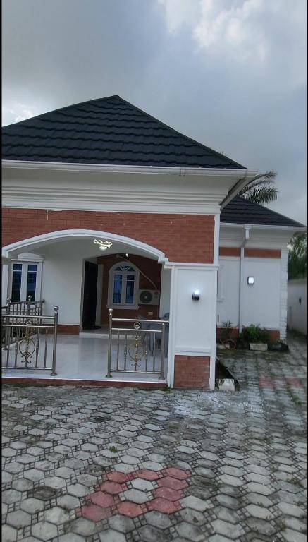 une maison avec une terrasse couverte et deux bancs devant elle dans l'établissement Contemporary 1 bedroom apartment in awoyaya ibeju lekki, à Awoyaya