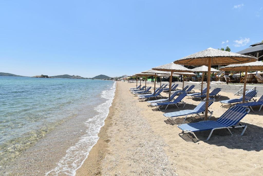 a row of chairs and umbrellas on a beach at Edem Luxury Apartments in Nea Peramos