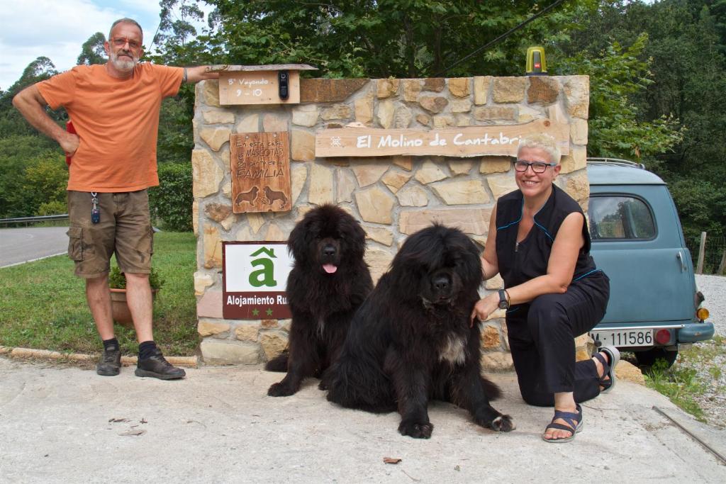 Um homem e uma mulher sentados ao lado de dois cães negros. em Posada Pet Friendly El Molino de Cantabria em Entrambasaguas